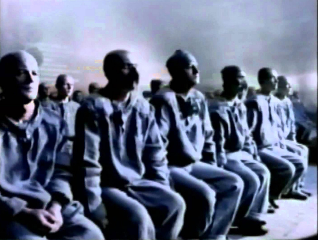 meetings are a mess: a screenshot from Apple's famous "1984" commercial of uniformed men sitting on benches, staring forwards