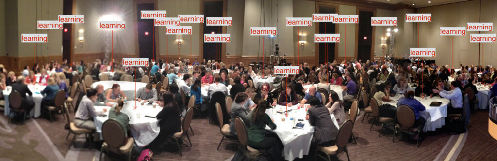 connection and learning at large meetings: a photograph of a large conference session with participants meeting around round tables. Arrowed notations "learning" are scattered throughout the room.